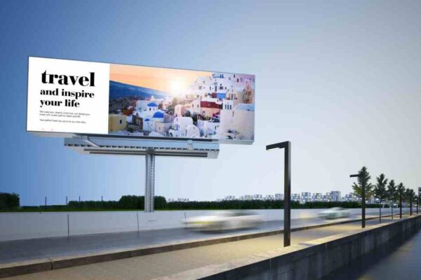 A large white roadside billboard with the image of a small town with the message "Travel and Inspire Your Life."