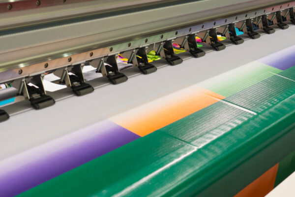 Close-up of a colorful vinyl banner emerging from a wide-format printer with a striking, blocky design.