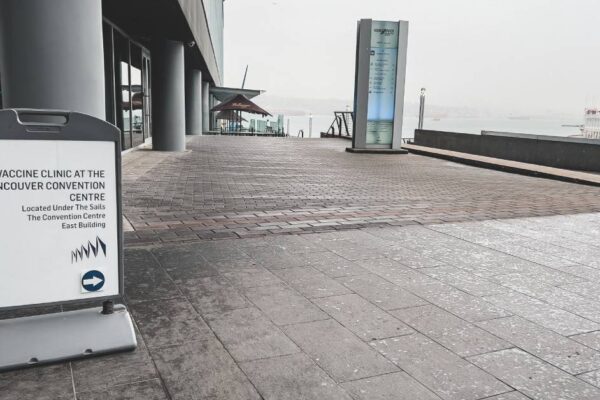 A sign is seen in front of a convention center indicating the direction to a vaccine clinic and other information.