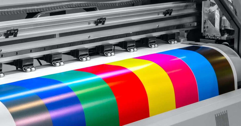 Close up on a wide-format printer turnign out a big printed sheet featuring large blocks in different colors.