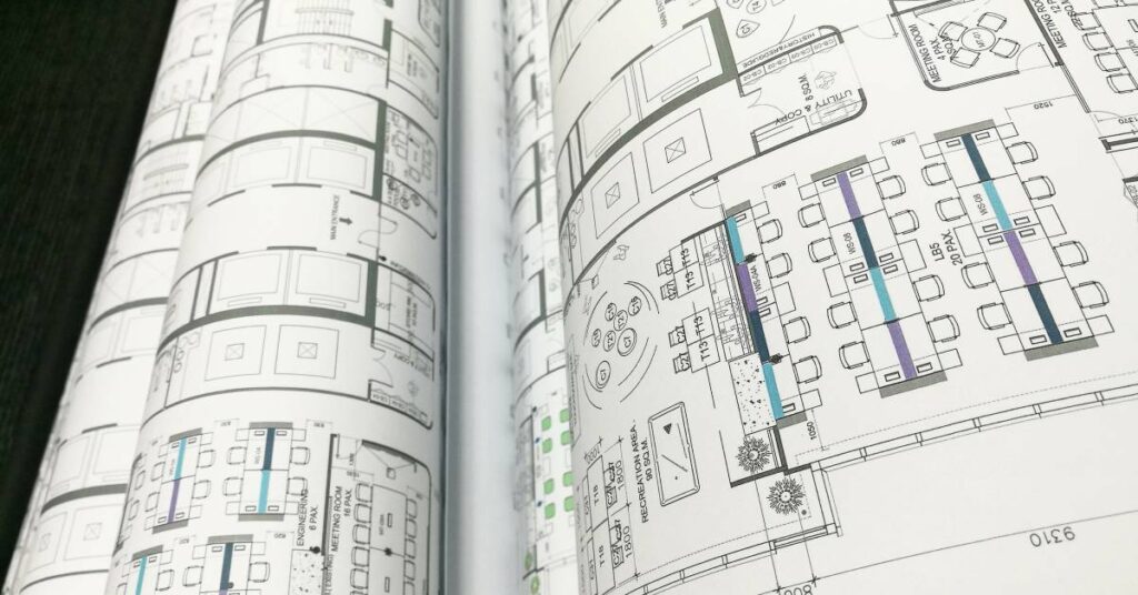 A close-up on several semi-rolled-up sheets of plotter paper displaying a building layout and design.