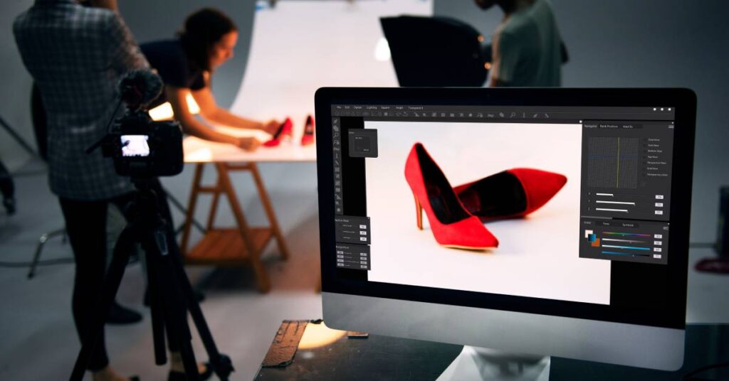 Three people work together in a photographer's studio, setting up a pair of red high heels for a photo shoot.