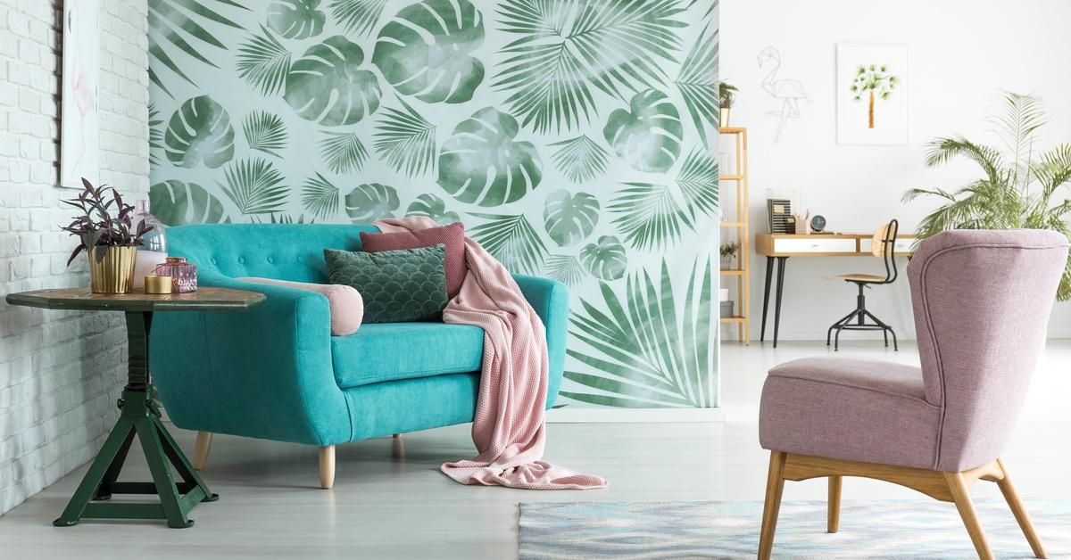 A living room featuring a printed partition wall with green leaf graphics. Two chairs and a side table sit in front.